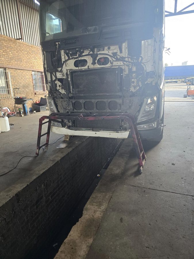 Front of a Volvo tractor unit opened up over the pit for an HGV mechanic test
